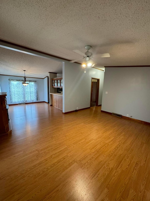 spare room featuring crown molding, ceiling fan with notable chandelier, light hardwood / wood-style floors, and a textured ceiling