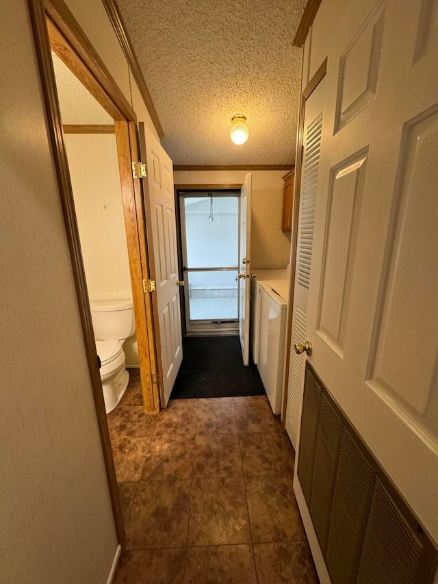 hall featuring washer and dryer, dark tile patterned floors, and a textured ceiling