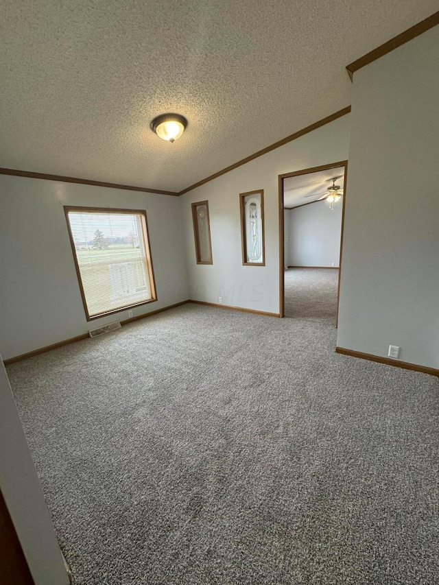 carpeted empty room featuring ceiling fan, ornamental molding, and a textured ceiling