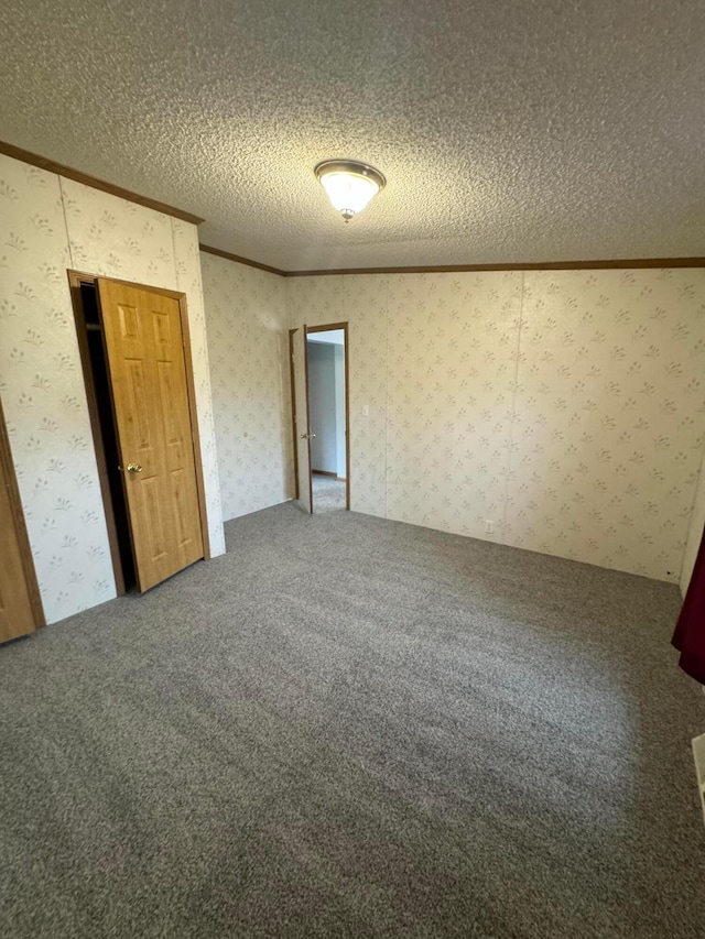 carpeted empty room with a textured ceiling and ornamental molding