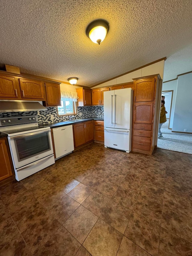 kitchen with backsplash, a textured ceiling, white appliances, vaulted ceiling, and dark tile patterned flooring