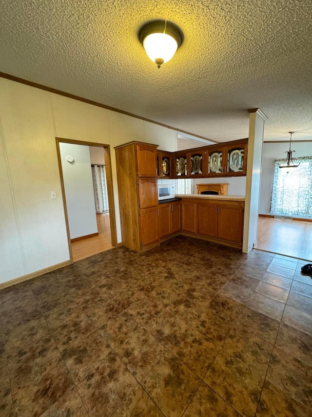 kitchen with crown molding, pendant lighting, and a textured ceiling