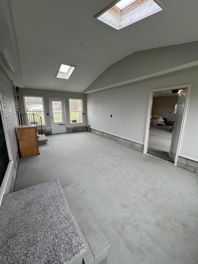 unfurnished living room featuring lofted ceiling with skylight