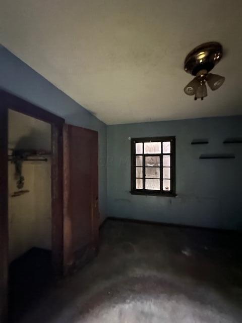 interior space with ceiling fan, concrete flooring, and vaulted ceiling