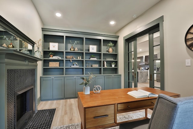 office space with light wood-type flooring and a tiled fireplace