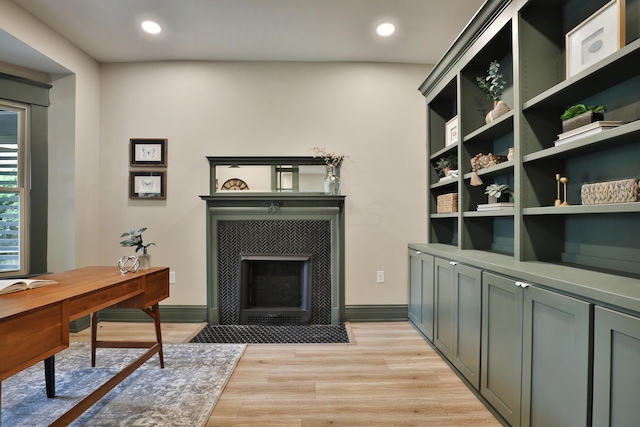 home office with a tile fireplace and light wood-type flooring