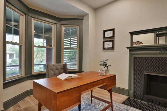 office space featuring a tiled fireplace and light hardwood / wood-style flooring