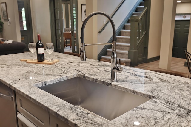 kitchen with light wood-type flooring, light stone counters, and sink