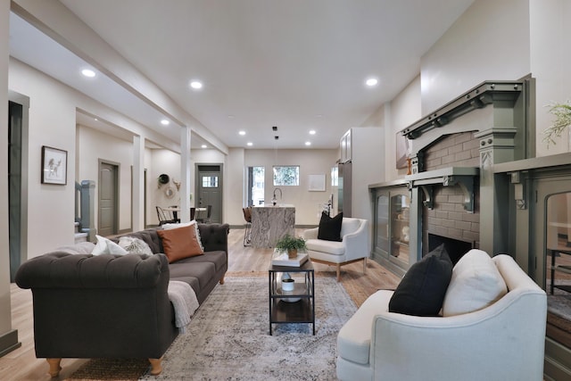 living room with a fireplace, light hardwood / wood-style flooring, and sink