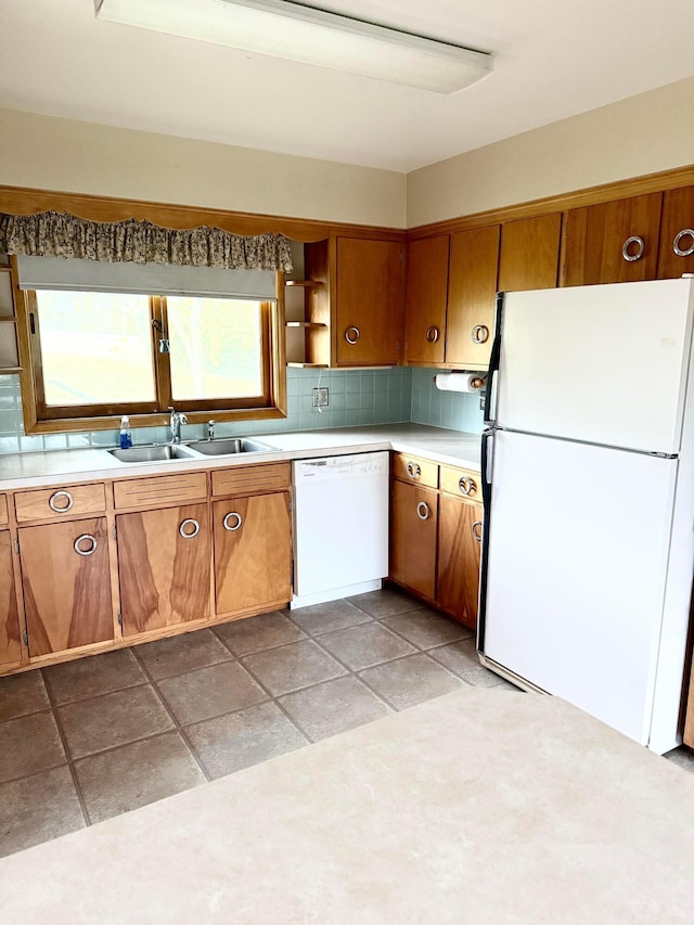 kitchen featuring brown cabinetry, open shelves, a sink, light countertops, and white appliances
