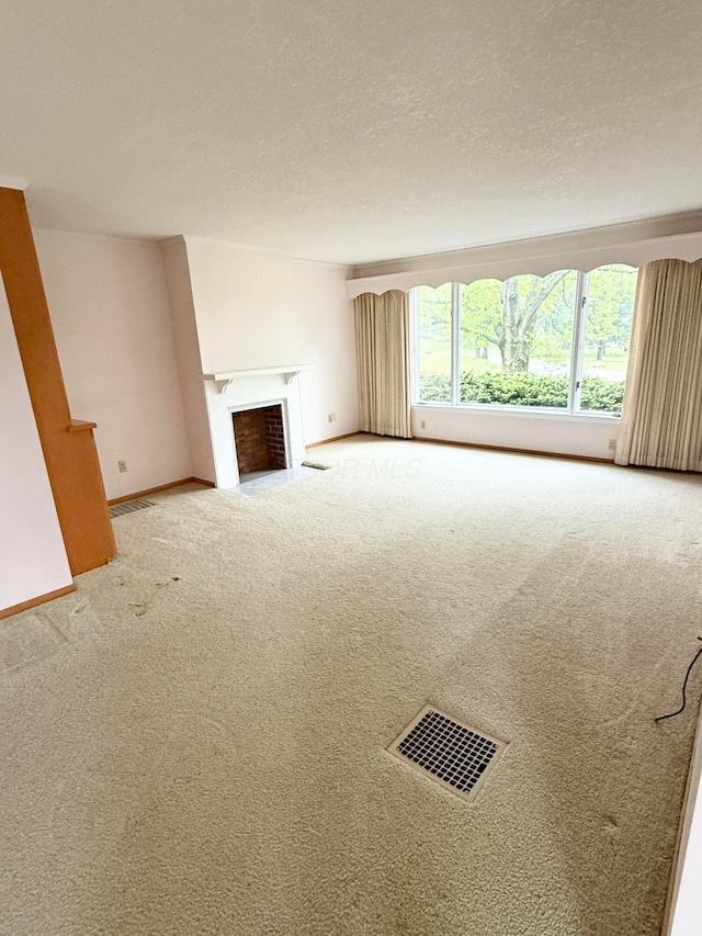 unfurnished living room featuring visible vents, carpet flooring, baseboards, and a fireplace with flush hearth