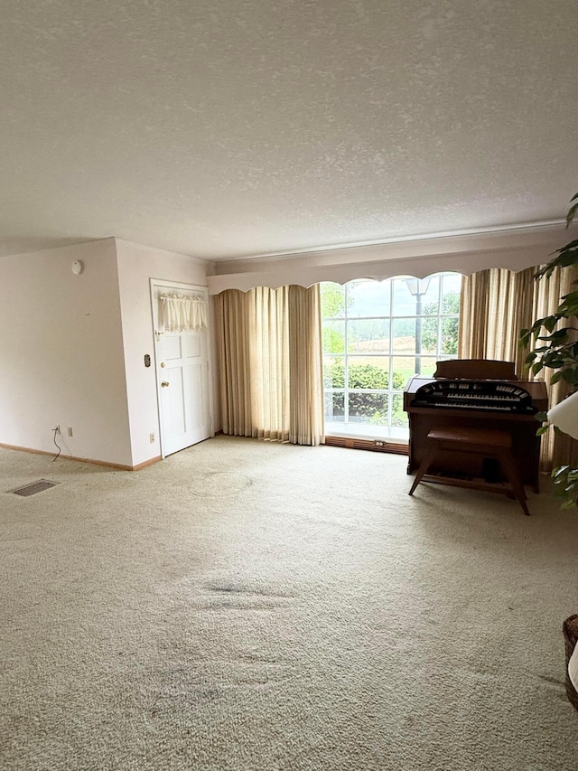 carpeted living room featuring baseboards, a textured ceiling, and visible vents