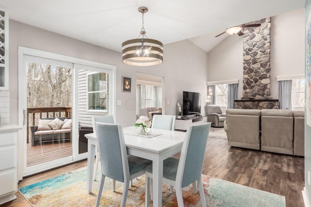 dining space with wood-type flooring, ceiling fan with notable chandelier, and vaulted ceiling