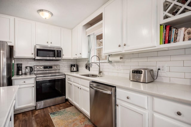 kitchen with appliances with stainless steel finishes, tasteful backsplash, sink, white cabinets, and dark hardwood / wood-style floors