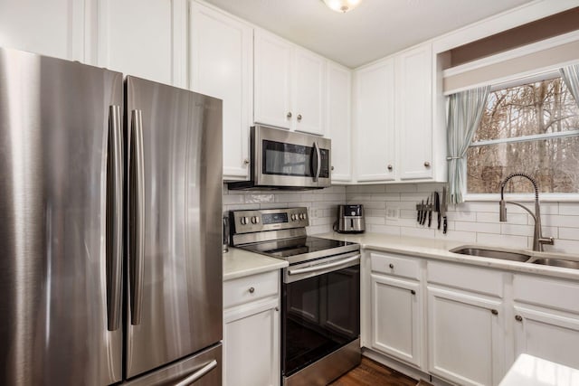 kitchen with tasteful backsplash, sink, white cabinets, and appliances with stainless steel finishes