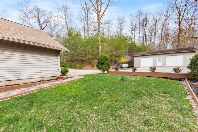 view of yard with a garage and an outbuilding