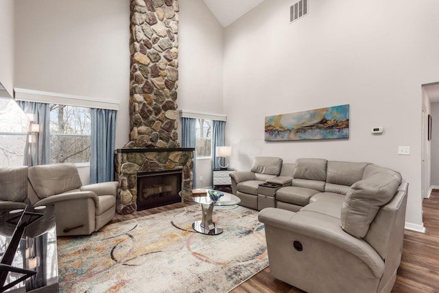 living room featuring a fireplace, dark hardwood / wood-style floors, high vaulted ceiling, and plenty of natural light