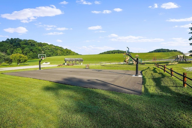 surrounding community featuring basketball hoop, a yard, and a rural view