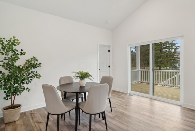 dining space featuring high vaulted ceiling and light wood-type flooring