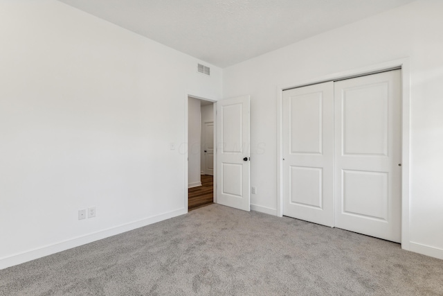 unfurnished bedroom with light carpet and a closet