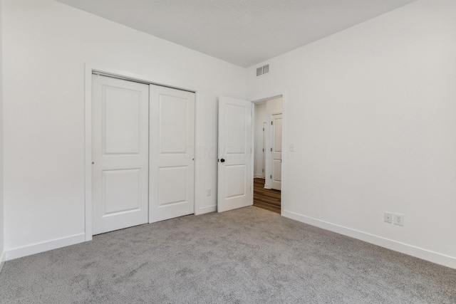 unfurnished bedroom with light colored carpet and a closet