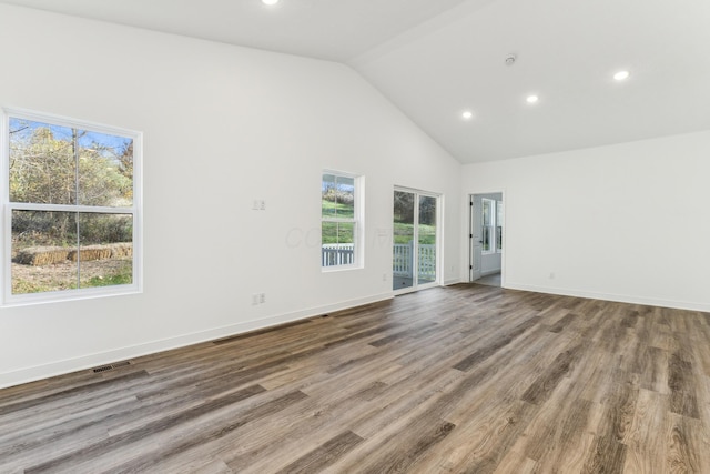 spare room featuring a wealth of natural light, high vaulted ceiling, and hardwood / wood-style flooring