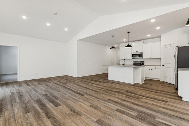 kitchen featuring stainless steel appliances, an island with sink, pendant lighting, lofted ceiling, and white cabinets