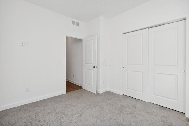 unfurnished bedroom with light colored carpet and a closet