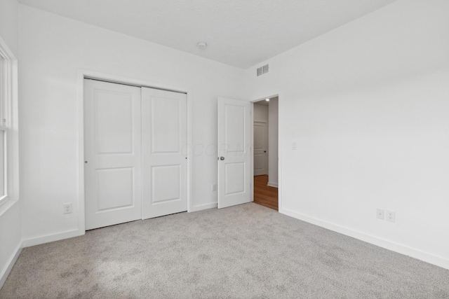 unfurnished bedroom featuring a closet and light colored carpet