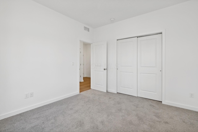 unfurnished bedroom with light carpet and a closet