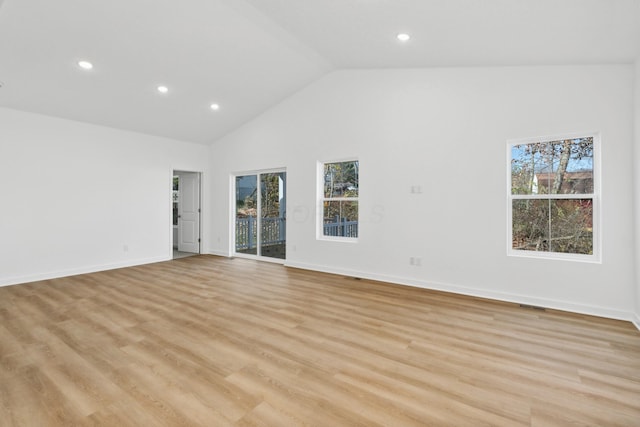 unfurnished room featuring plenty of natural light, light wood-type flooring, and high vaulted ceiling