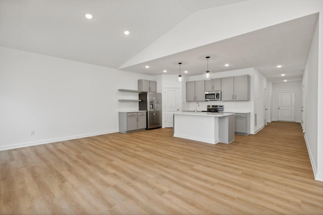 kitchen featuring appliances with stainless steel finishes, a center island with sink, decorative light fixtures, and gray cabinetry