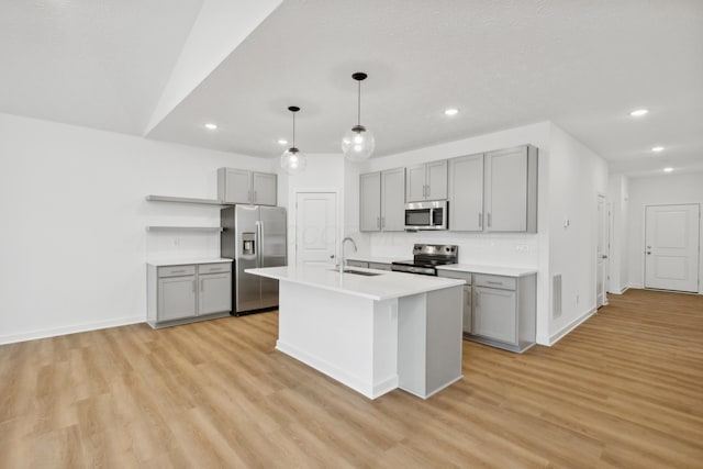 kitchen featuring appliances with stainless steel finishes, an island with sink, light hardwood / wood-style flooring, and sink