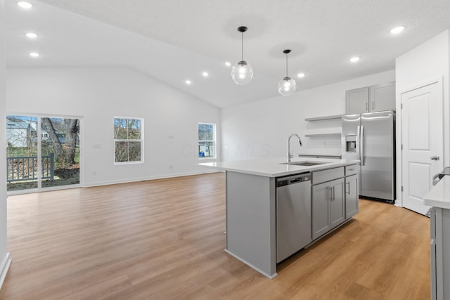 kitchen featuring appliances with stainless steel finishes, light hardwood / wood-style floors, sink, a center island with sink, and gray cabinets