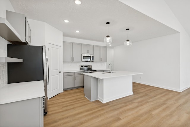 kitchen featuring decorative light fixtures, sink, appliances with stainless steel finishes, and light hardwood / wood-style flooring