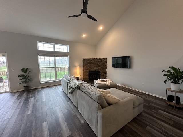 living room with a stone fireplace, ceiling fan, dark hardwood / wood-style flooring, and high vaulted ceiling