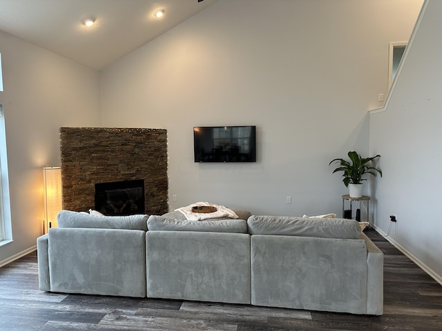 living room with a stone fireplace, high vaulted ceiling, and dark wood-type flooring