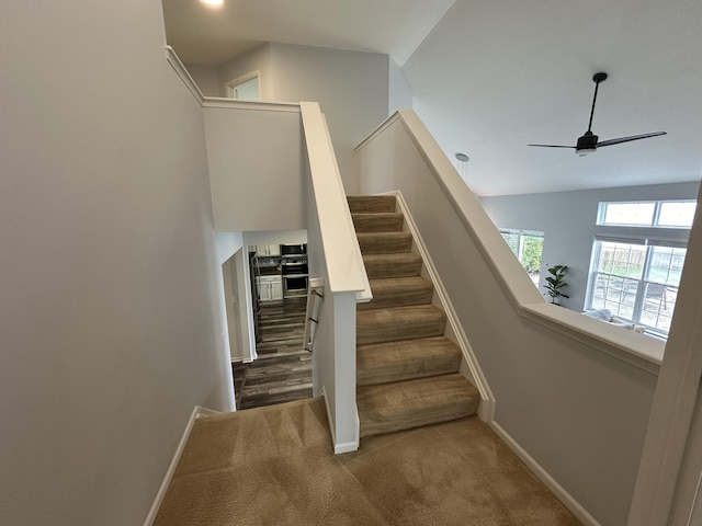 staircase with ceiling fan, carpet floors, and vaulted ceiling