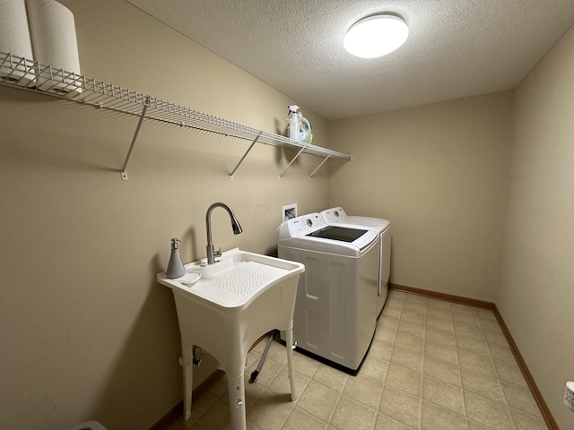 washroom with sink, washer and dryer, and a textured ceiling