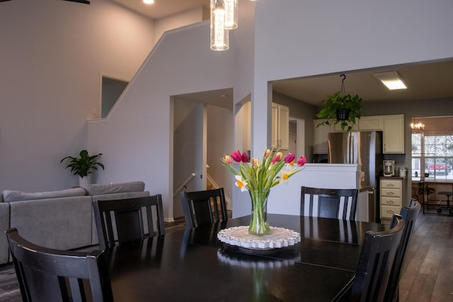 dining area featuring a towering ceiling, dark hardwood / wood-style flooring, and a notable chandelier