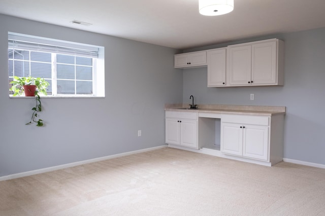 kitchen featuring sink, white cabinets, and light colored carpet