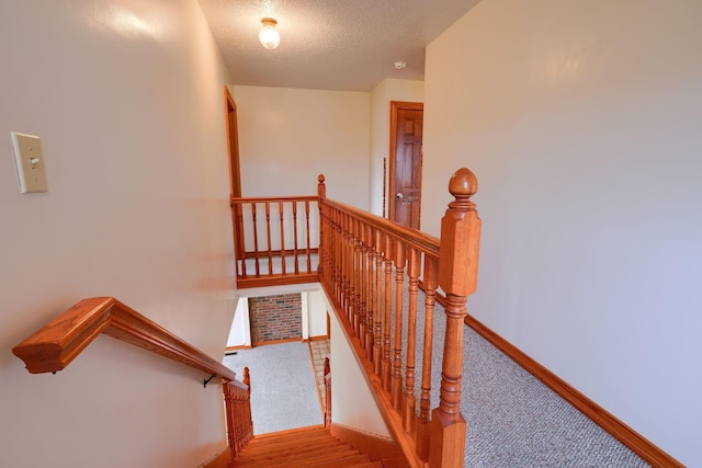 staircase with hardwood / wood-style floors and a textured ceiling