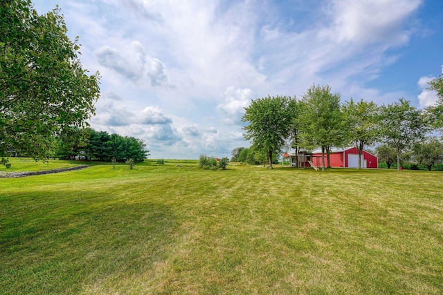 view of yard featuring a rural view, an outbuilding, and a garage