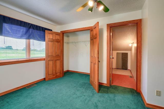 unfurnished bedroom with dark colored carpet, a textured ceiling, a closet, and ceiling fan