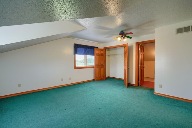 unfurnished bedroom with vaulted ceiling, ceiling fan, a textured ceiling, carpet floors, and a closet