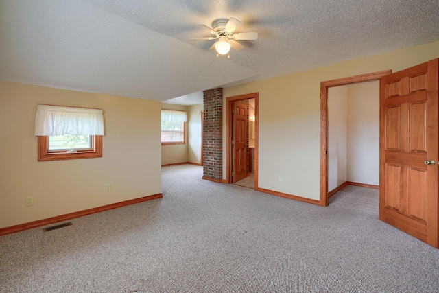 spare room with a textured ceiling, light colored carpet, a wealth of natural light, and ceiling fan