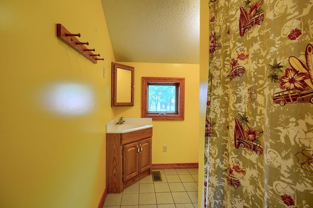 bathroom featuring tile patterned floors, vanity, a textured ceiling, and vaulted ceiling