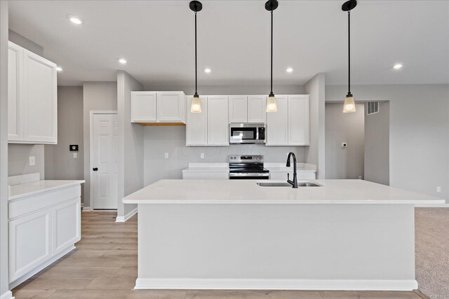 kitchen featuring pendant lighting, a kitchen island with sink, sink, white cabinetry, and stainless steel appliances