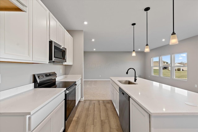 kitchen with stainless steel appliances, sink, light hardwood / wood-style floors, white cabinetry, and hanging light fixtures