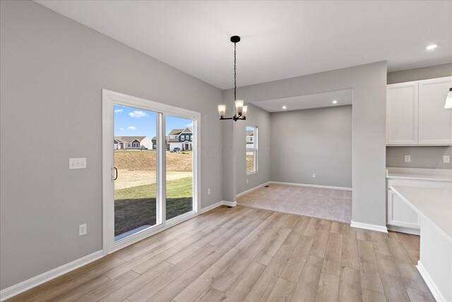 unfurnished dining area featuring a chandelier and light hardwood / wood-style flooring